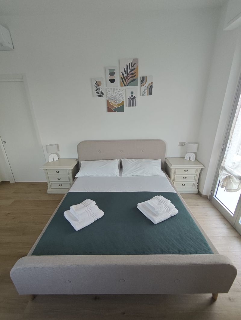 Doppelschlafzimmer mit Nachttischen und Balkonzugang
