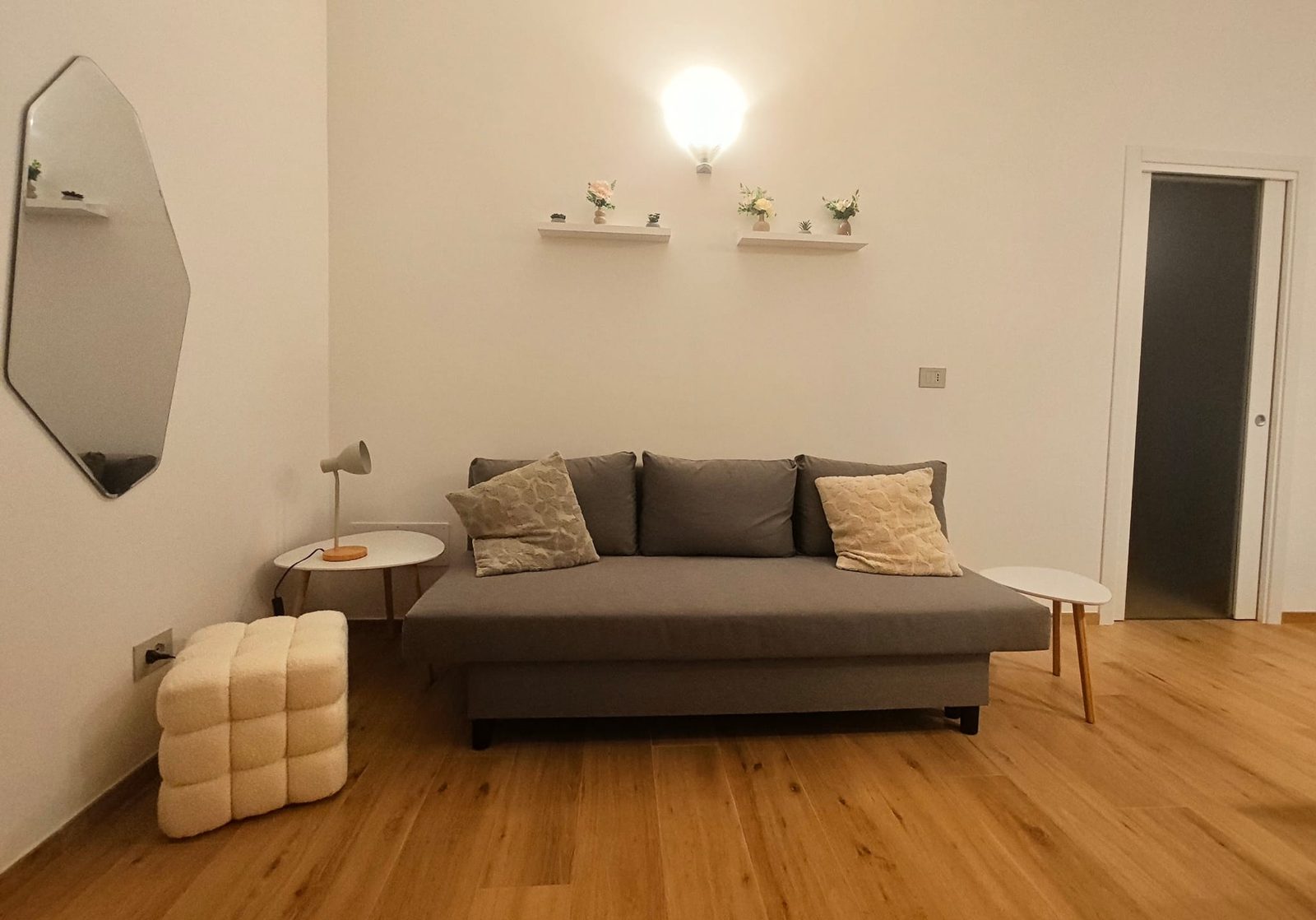 Wohnbereich mit grauem Schlafsofa und Spiegel
