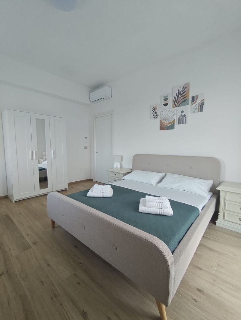 Schlafzimmer mit grüner Tagesdecke und weißem Schrank